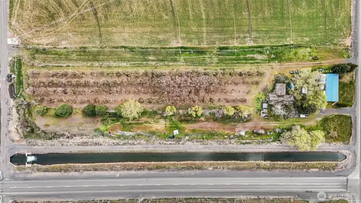 The property is the whole rectangle, two parcels, and is bordered by the canal and the driveway on the far side of the manufactured home.