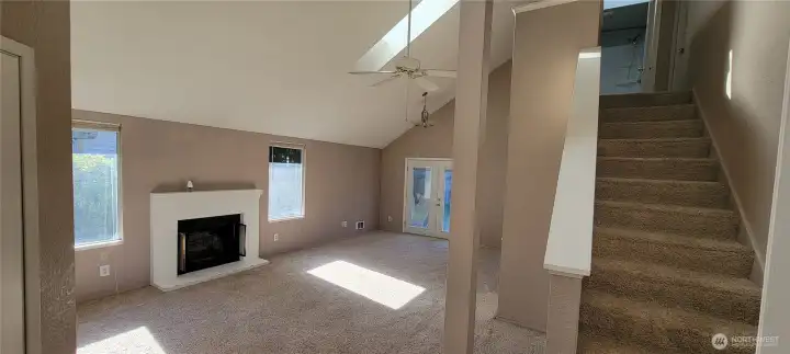 Wood burning fireplace flanked with windows and a view of the dining room.