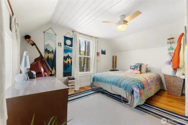 Upstairs bedroom with soft wood floors. and a ceiling fan.