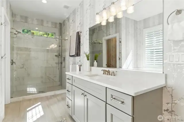 Separate walk in shower with tiled floor and walls and tempered glass door. The separate commode room is to the left of the shower.