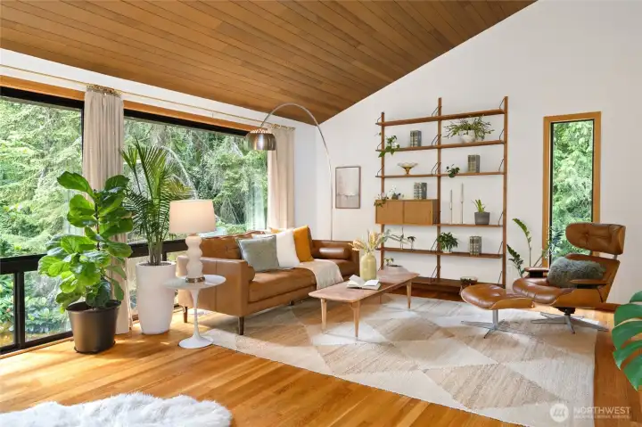 The spacious living room looks out to serene treed views through large picture windows.