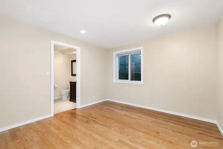 Spacious lower-level primary suite with attached bath and elegant hardwood flooring