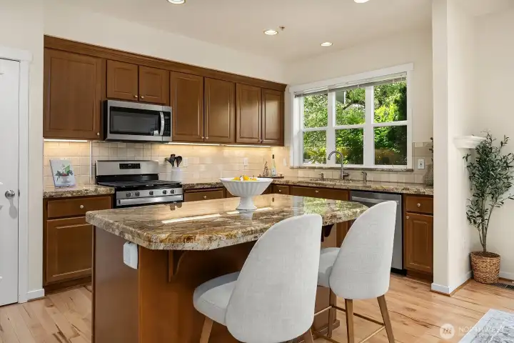 The upgraded kitchen featuring a perfectly sized island, granite counters and new appliances