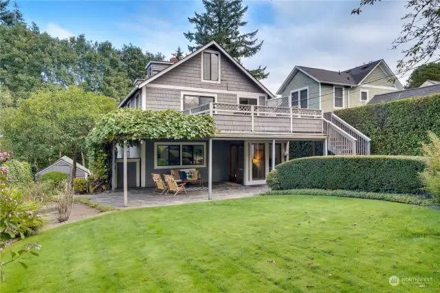 Lush gardens, gracefully covered by wisteria and bordered with elegant stone pavers, creating a serene and picturesque outdoor setting.