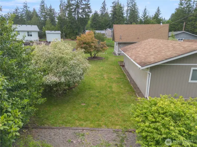 Behind the home with mature trees - but nothing huge that looms over the home.
