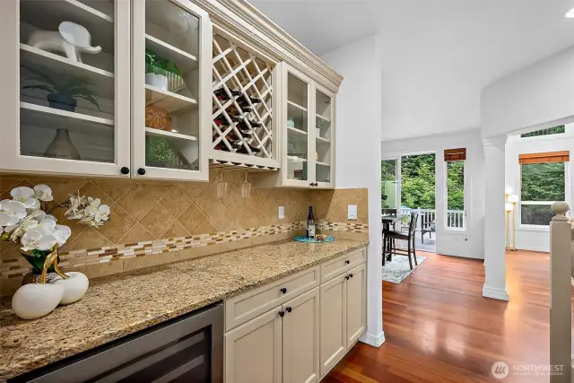 Butler pantry is located between the formal dining room and kitchen and has granite counters with full tile backsplash, custom cabinetry with wine rack and a stainless steel wine/beverage fridge.