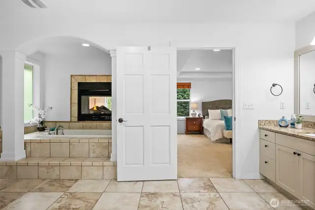 A spacious 5-piece bathroom with a huge walk in closet, soaking tub with full tile surround, a tile wrapped gas see through fireplace and fully tiled art niche.