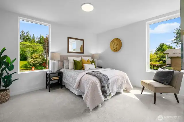 Corner bedroom wrapped in windows—light, bright, and sized for full furnishings. Photos are of model home 8825, finishes and floorplan may vary.