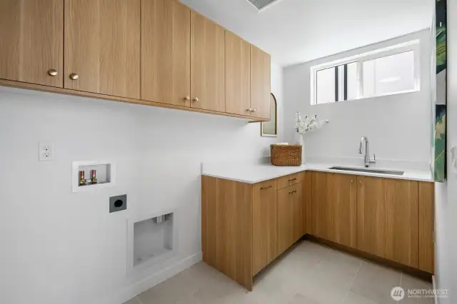 Dedicated laundry room with full cabinetry, utility sink, and folding counter keeps chores contained. Photos are of model home 8825, finishes and floorplan may vary.