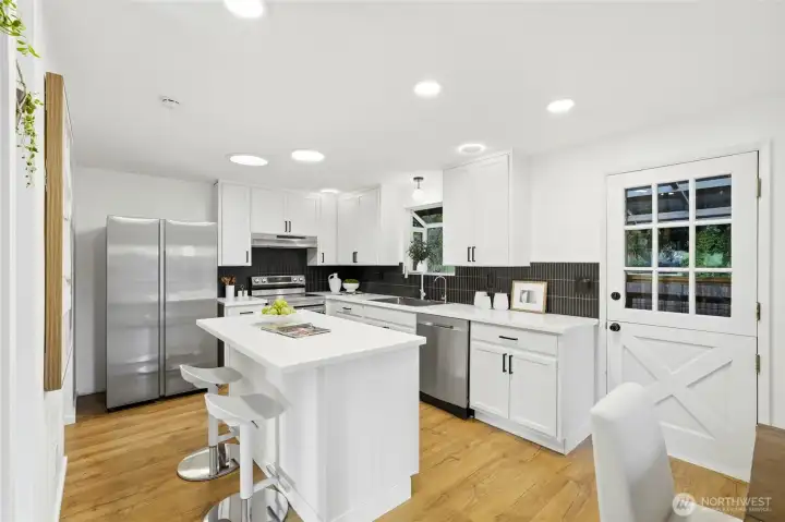 Updated kitchen with white cabinetry, stainless steel appliances, and center island.