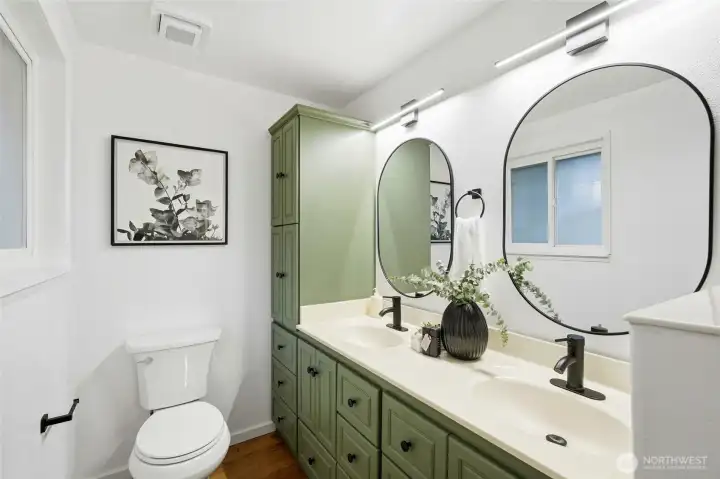 Full primary bathroom with double vanity, large mirror, and updated lighting.