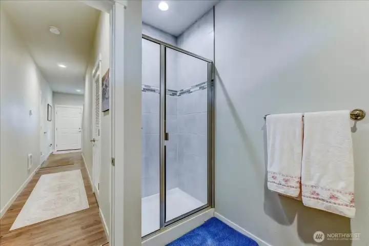 View of the lower 3/4 bath and hallway to the entry of the home. Garage entry is on the left side.