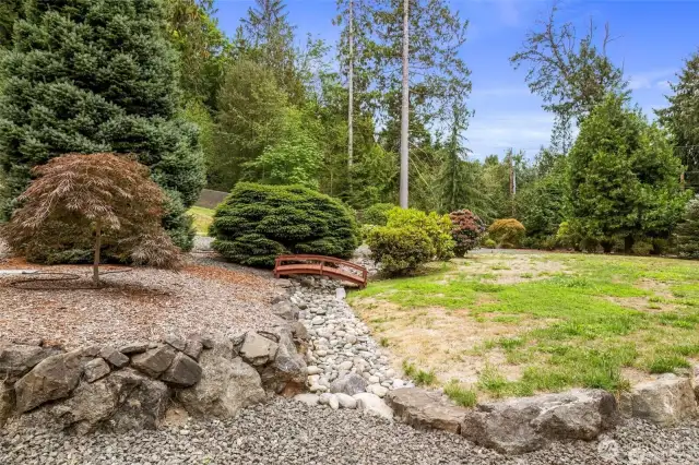 A decorative stone dry creek bed with a bridge.