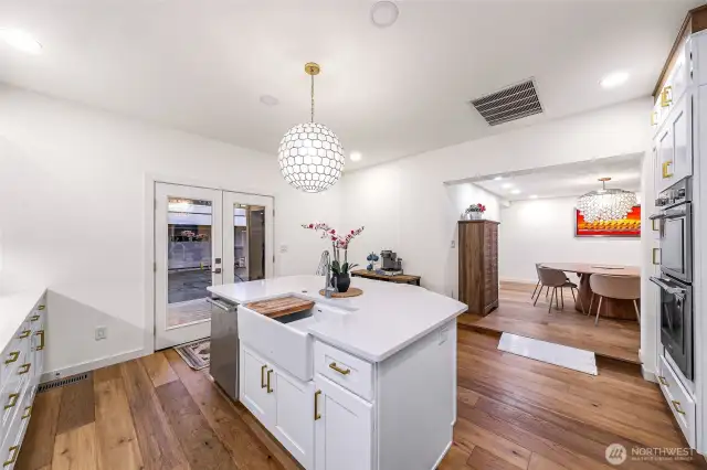 Island features apron-front farmhouse sink, gold-accent hardware, and access to the patio.