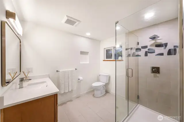 Updated bathroom with glass shower, bold tile accents, and modern fixtures.