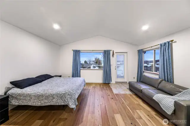 Upstairs primary suite with vaulted ceilings, windows, and balcony access.