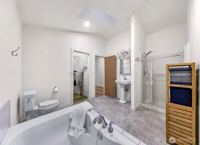 Spacious bath with tile floors, walk-in shower, pedestal sink, and walk-in closet access.