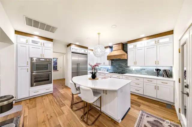 The chef’s kitchen is a showstopper, featuring $33K in Thermador appliances, white shaker cabinets, quartz counters, and a striking tile backsplash.