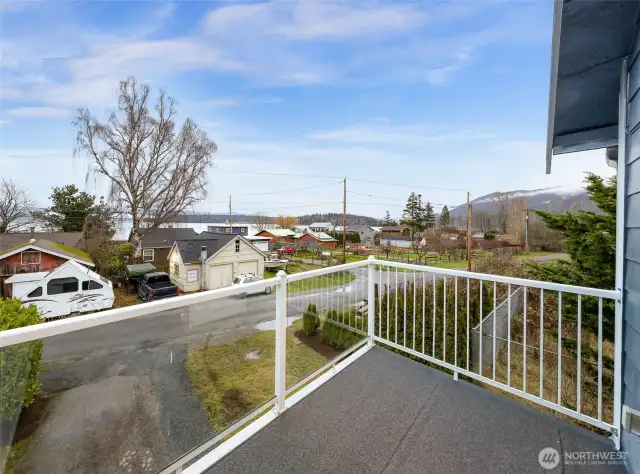 Upper-level balcony with views of neighborhood, trees, and distant mountains.