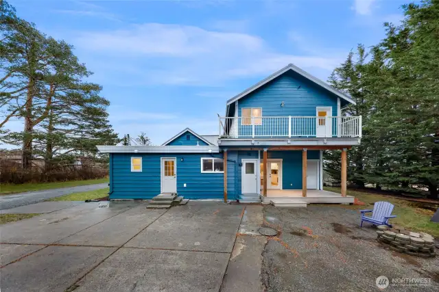 Rear view showcases two-story design with covered entry and upper balcony.