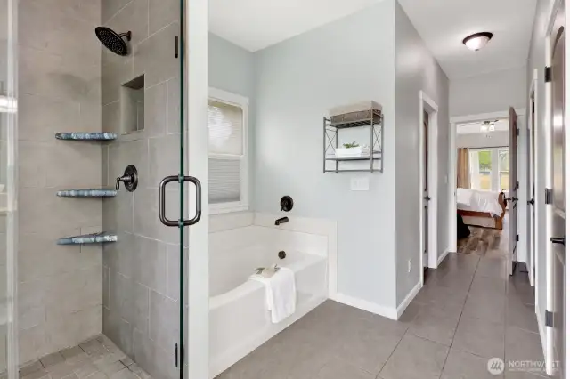 The primary bathroom features a large shower, soaker tub, and double closets