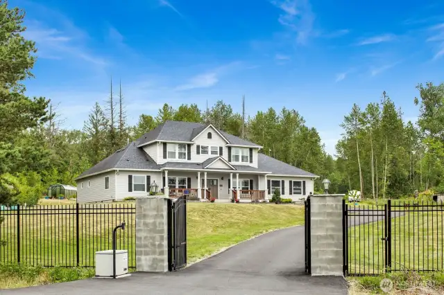 This grand residence is framed by a wrought-iron fence, paved driveway, RV parking, and a shop with ADU