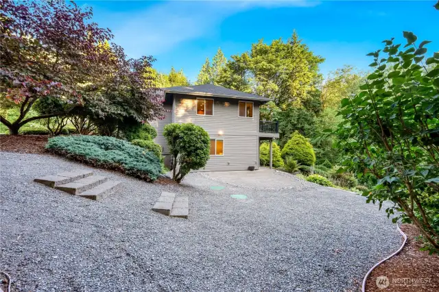 Side yard with professional landscaping, mature trees, and ample parking—curb appeal and comfort combined.