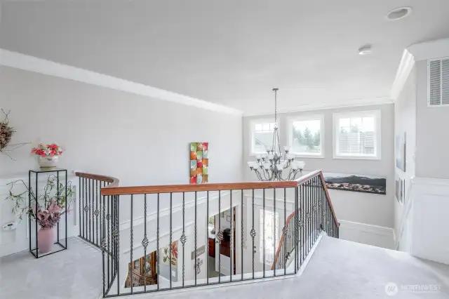 Upper floor landing with crown moulding and open rail stair system.