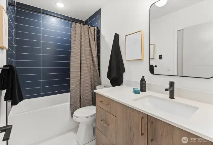 Bold navy tile adds depth and drama to this spa-inspired bath with sleek black hardware and premium finishes.