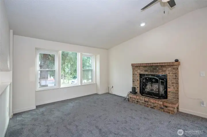 Warmth and charm fill the living area with a brick wood fireplace and new carpet.