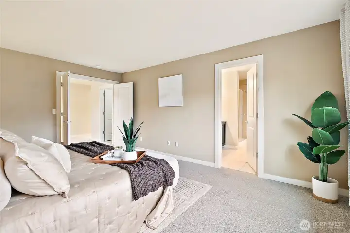 Double doors create a grand entrance to the spacious primary bedroom.