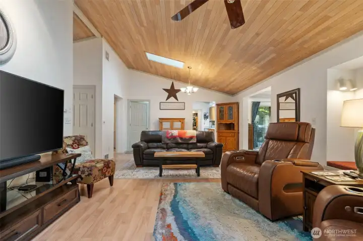 Living room toward kitchen, window seat on right, dining room w/large slider to deck on right, entry hall on left.