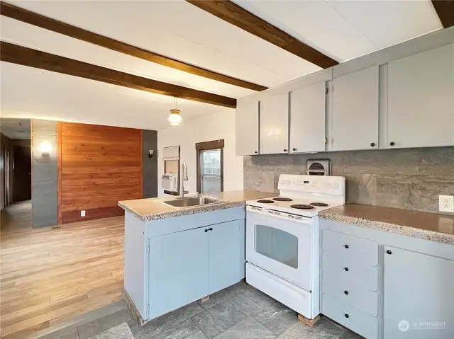 Open floor plan includes a kitchen with tile floors and backsplash.