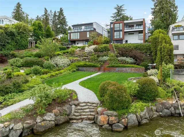 Beautifully landscaped low bank waterfront, large grassy area, stone path from dock to residence and fire pit