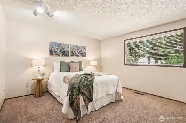 Primary bedroom overlooks the yard and has its own private bath and walk in closet