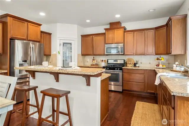 View of the kitchen from the back door. Bar height counter, walk-in pantry, and plenty of cabinetry make this kitchen a dream!