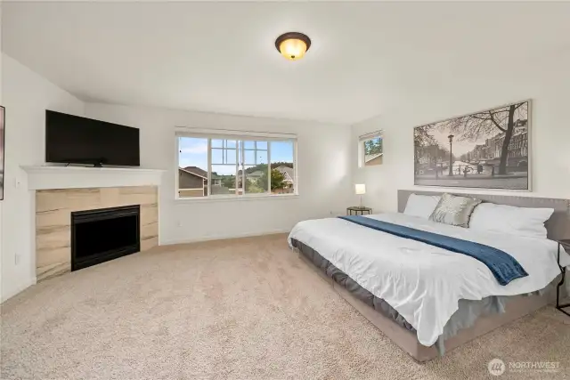 Primary suite, as seen from the double door entrance! Overlooking the front yard with plenty of natural light and a fireplace in the corner!