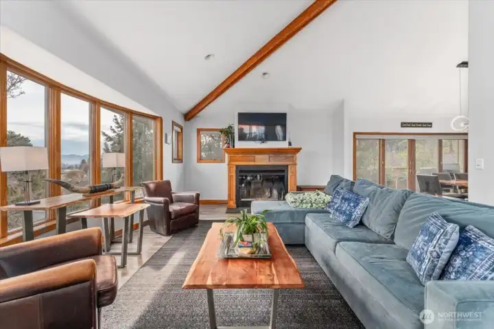 Mail level living room with vaulted ceilings and wood burning fireplace.