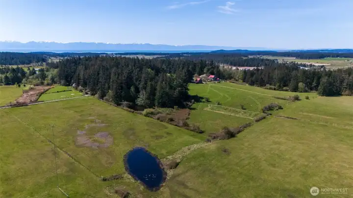 Aerial looking southwest, of the twenty acre parcel with ponds, forest, pastures, home, guesthouse, apartment, barns, and more, centrally located on Lopez Island