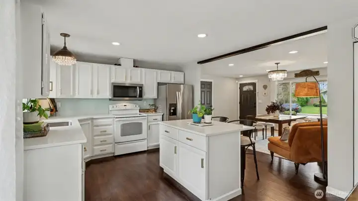 Kitchen gleams with natural light, quartz counters, stylish gold hardware, and new light fixtures.