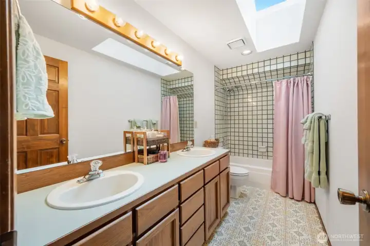 Full bathroom with double sinks and shower and bathtub.