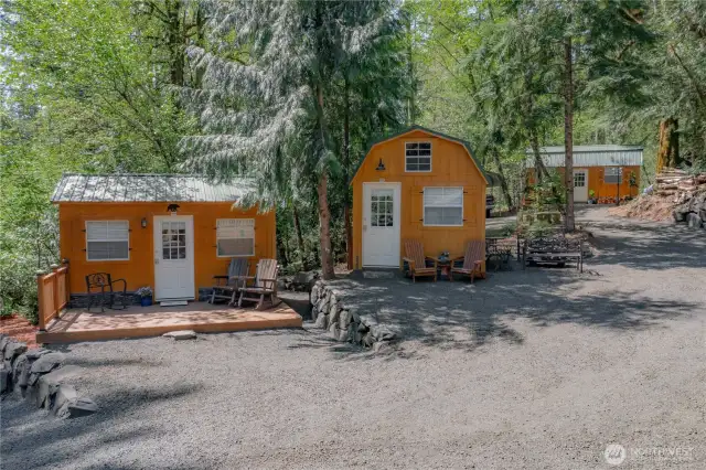 Beautifully matching sheds offer versatile options for storage or potential living space, thoughtfully placed among the trees on the property