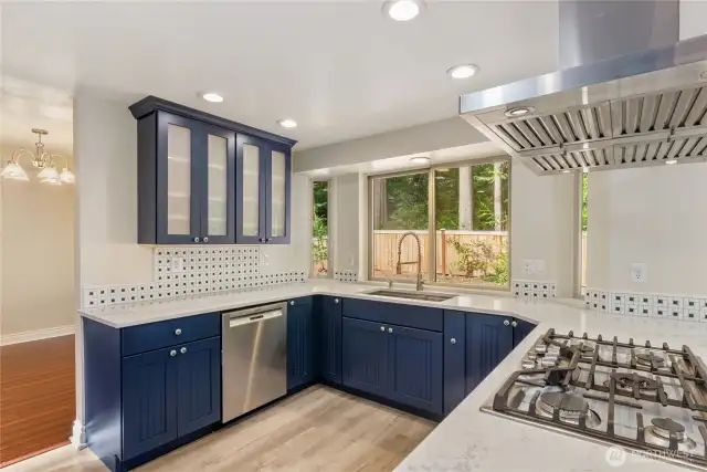 Alt view of kitchen with Bosch dishwasher, quartz counter tops, tile backsplash.