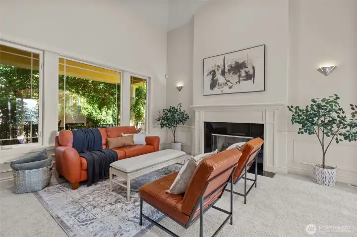 Refined living space featuring a cozy fireplace, custom millwork, and large windows overlooking lush greenery. Refined living space featuring a cozy fireplace, custom millwork, and large windows overlooking lush greenery.