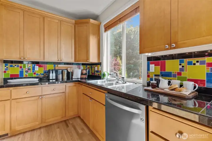 Bright kitchen workspace with large windows, tile backsplash, and functional layout designed for everyday living.