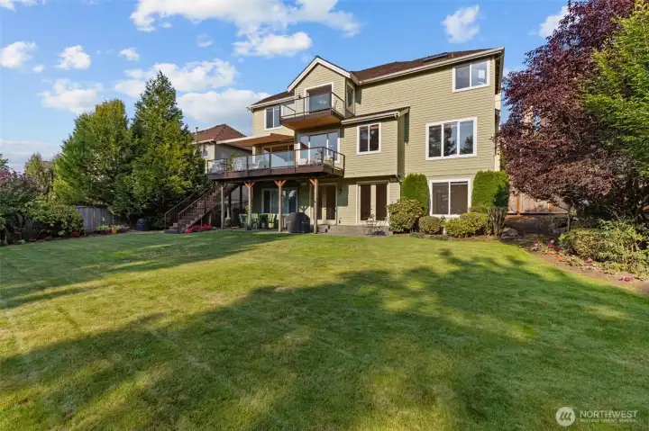 Expansive backyard and rear elevation showcasing multiple outdoor living areas and mature landscaping.