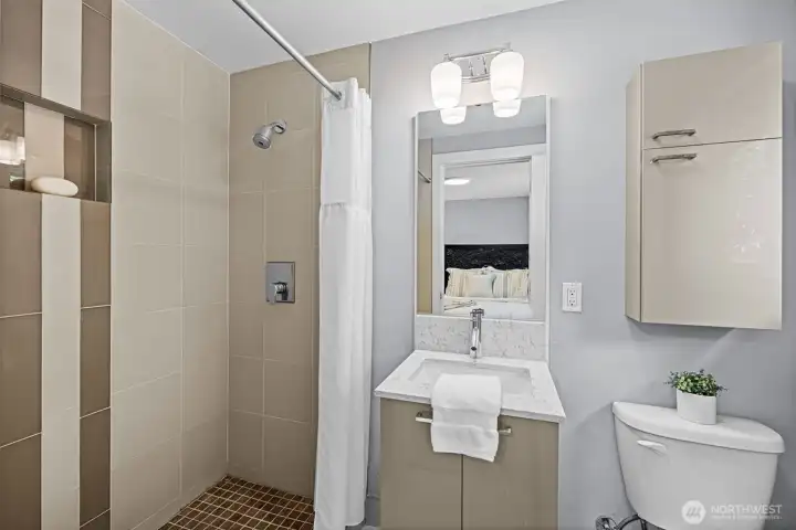 Low curb walk in shower, sleek vanity, and storage cabinet.