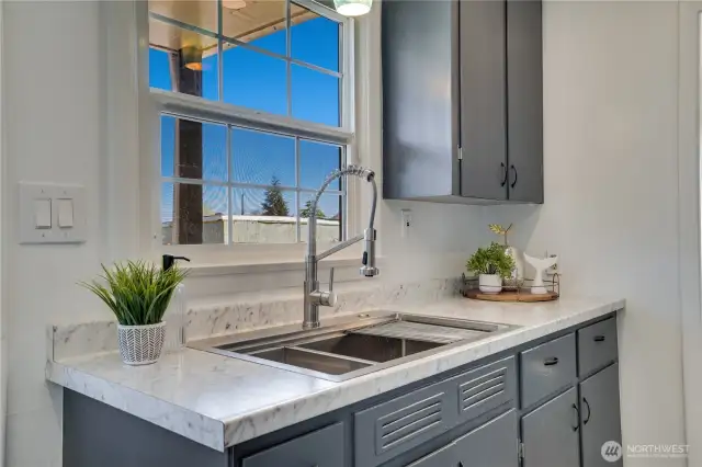 A window over the double-basin stainless sink looks out to the back yard.