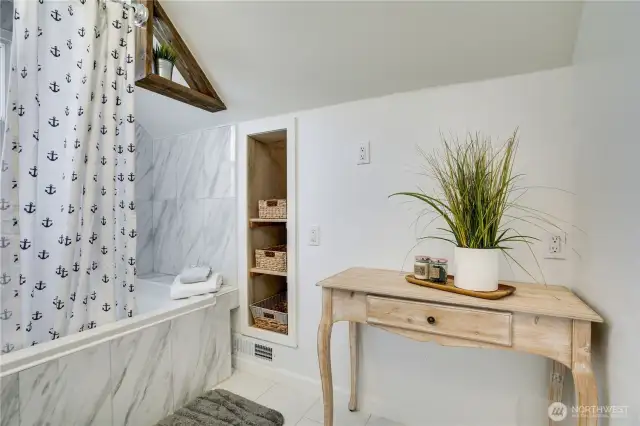 Shelving built into the wall offers a place for tucking supplies away in this updated bathroom.