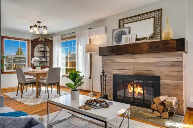 The fireside living room adjoins a dining area on the bright main floor. Notice the ductless heating & cooling unit on the wall. This home is also equipped with a gas furnace, so the ductless units are especially useful for summertime cooling.
